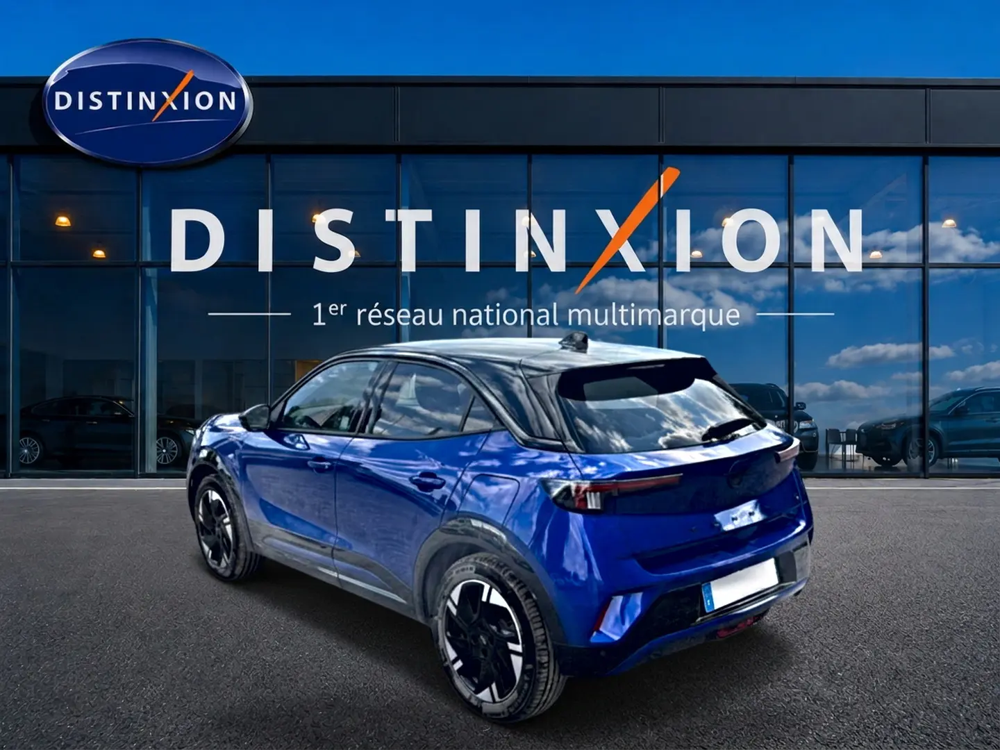 Opel Mokka Electric bleu en 3/4 arrière droit, toit noir brillant et jantes alu distinctives.