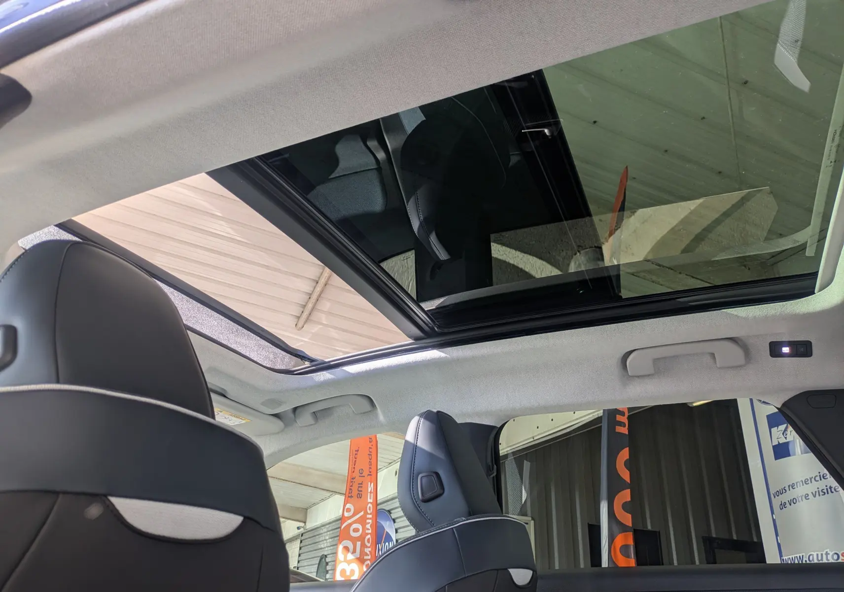 Vue intérieure du toit panoramique ouvert du Citroën C5 Aircross gris platinium avec sièges avant en cuir noir.