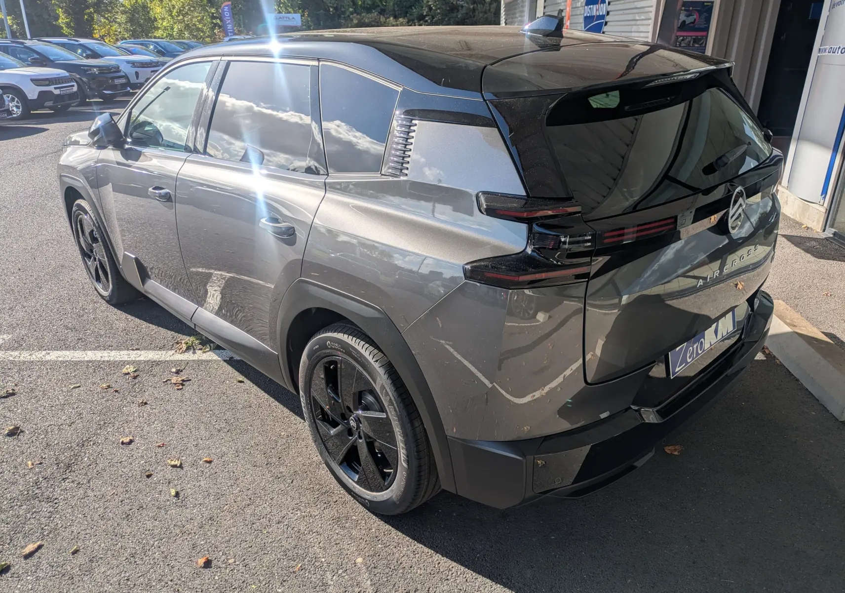 Vue 3/4 arrière droite d'un Citroën C5 Aircross hybride gris platinium avec toit noir et jantes noires.