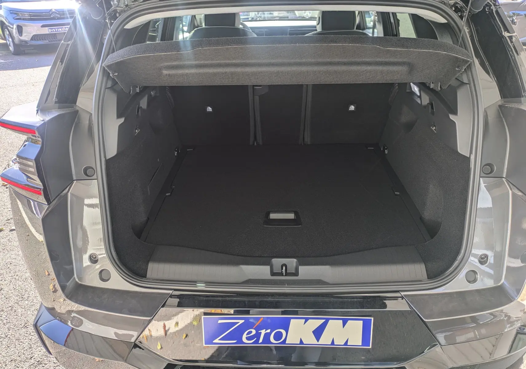 Coffre ouvert vu de l'arrière d'un Citroën C5 Aircross gris platinium avec toit noir, montrant l'espace de chargement vide.