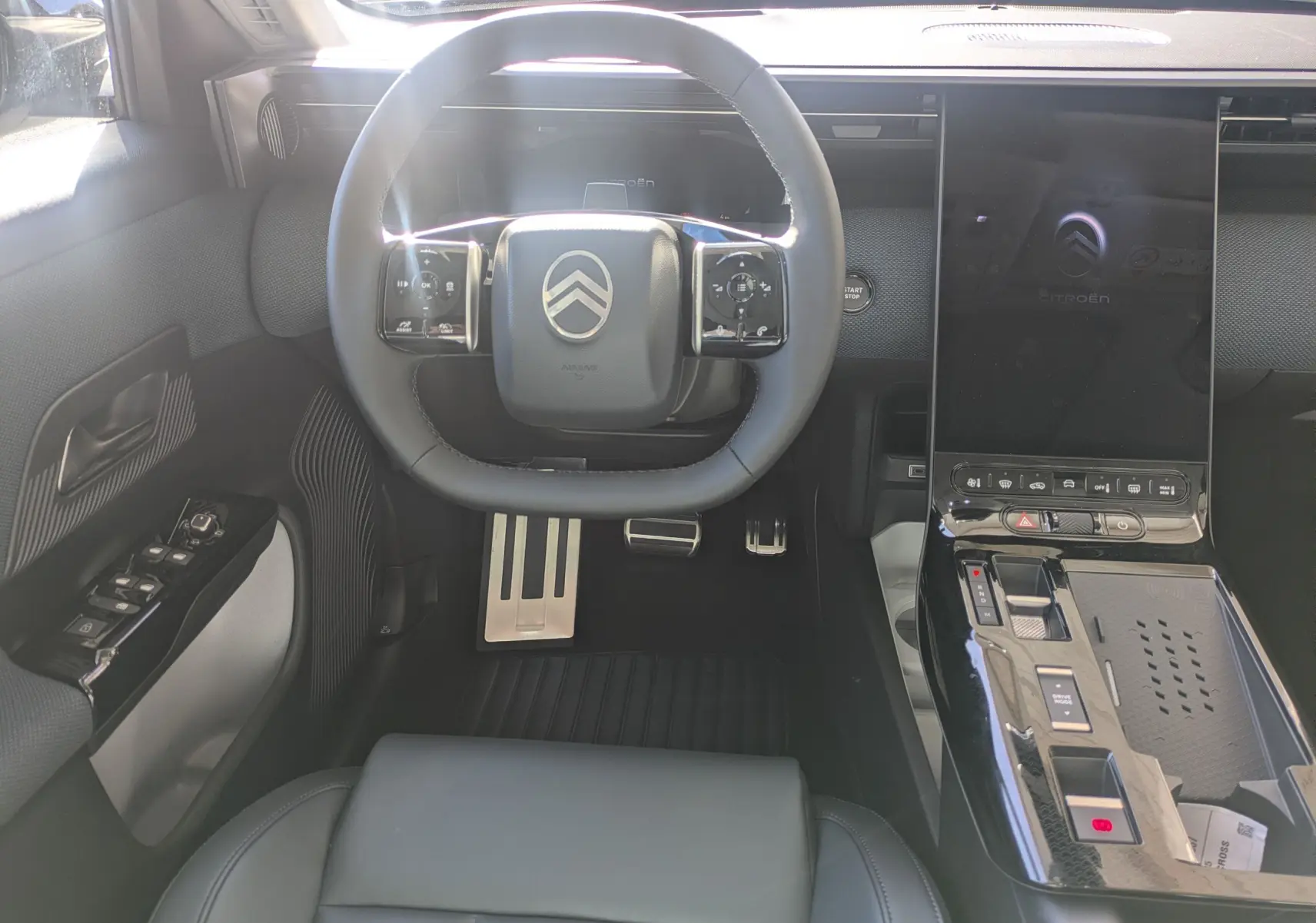Vue intérieure avant centrée sur le volant noir et la console centrale brillante du Citroën C5 Aircross hybride 2026.