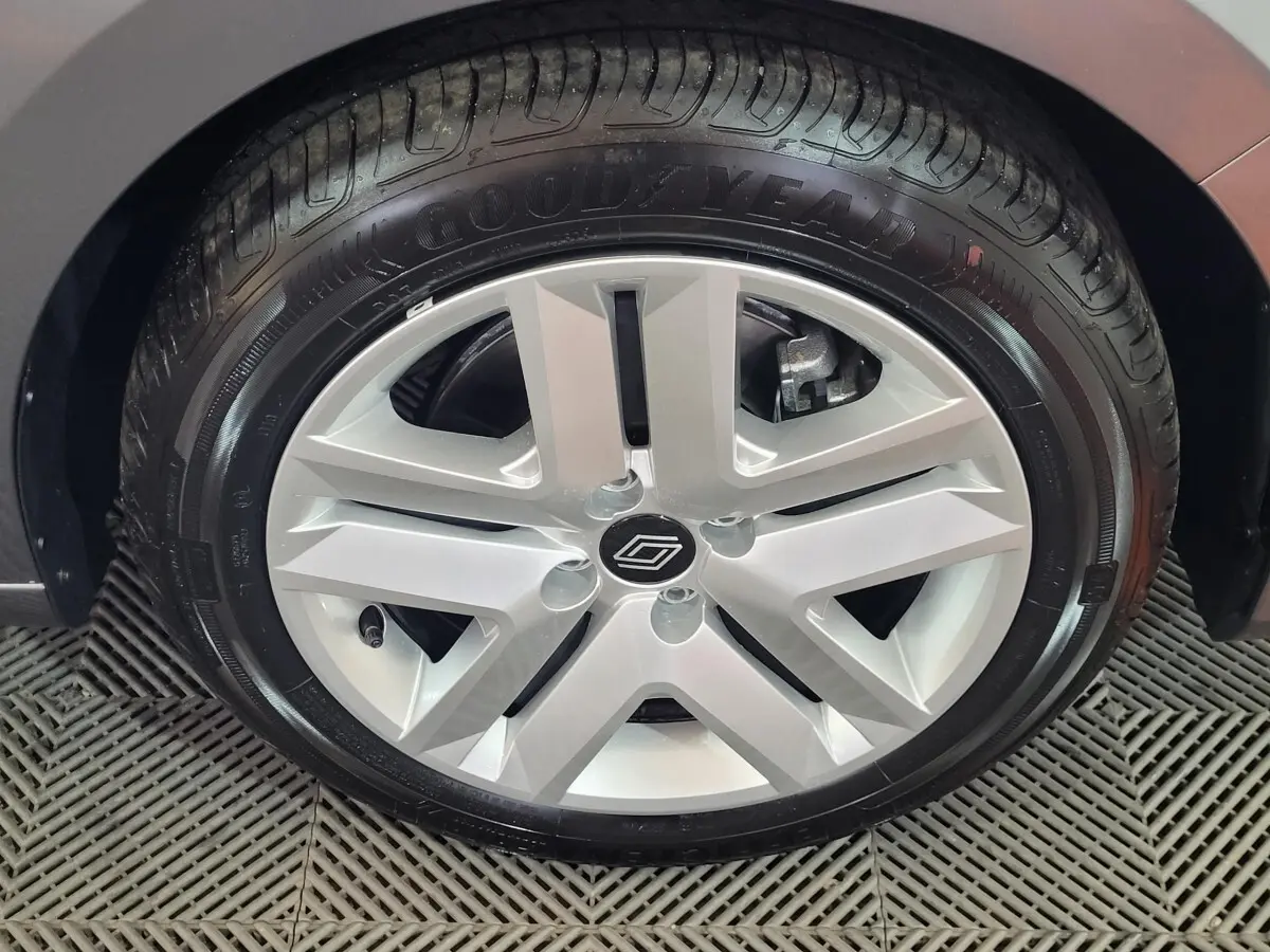 Gros plan sur la roue arrière droite d'une Renault Clio gris foncé, mettant en valeur le pneu et l'aile du véhicule.