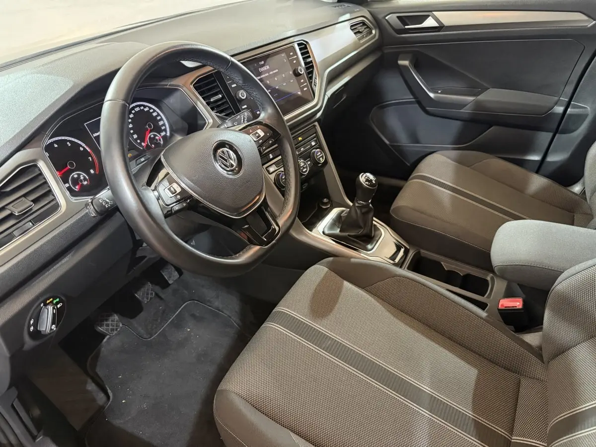 Intérieur noir du Volkswagen T-Roc 1.0 TSI 115 Lounge Business, vue côté conducteur sur volant cuir et console centrale.