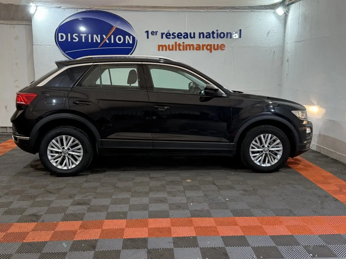 Profil côté gauche d'un Volkswagen T-Roc noir 2020 garé en intérieur avec jantes alliage et rails de toit noirs.