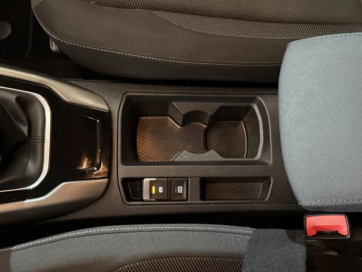 Gros plan sur la console centrale noire du Volkswagen T-Roc 2020, montrant le frein à main électrique et porte-gobelets.