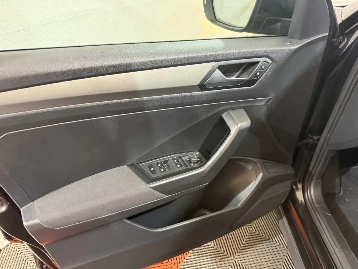 Vue rapprochée de la porte avant gauche noire du Volkswagen T-Roc 2020 avec commandes électriques et poignée angulaire.