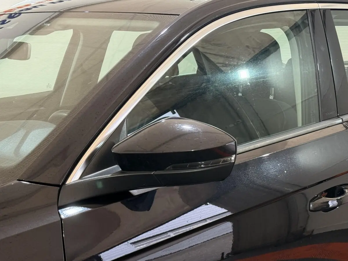 Gros plan sur le rétroviseur côté gauche d'un Volkswagen T-Roc noir 2020 avec portière et vitre avant visibles.