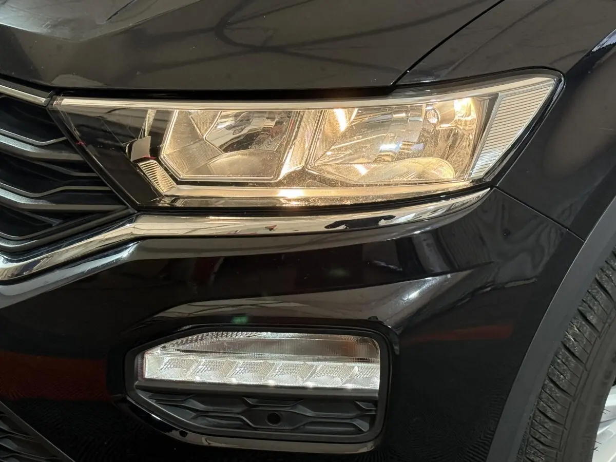 Gros plan sur le phare avant droit et antibrouillard d’un Volkswagen T-Roc noir, finition Lounge Business 2020.