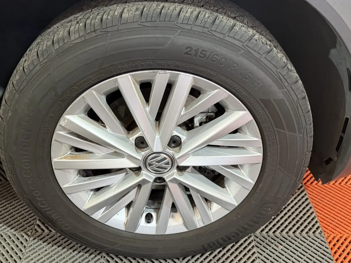 Gros plan sur la roue avant droite du Volkswagen T-Roc noir, mettant en valeur la jante alliage à rayons multiples.