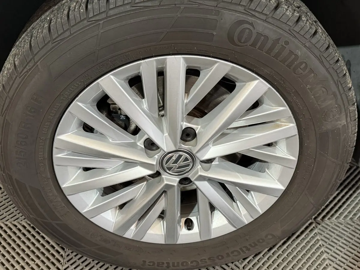 Gros plan sur la jante argentée en alliage d'une Volkswagen T-Roc noire, mettant en valeur le logo VW central.