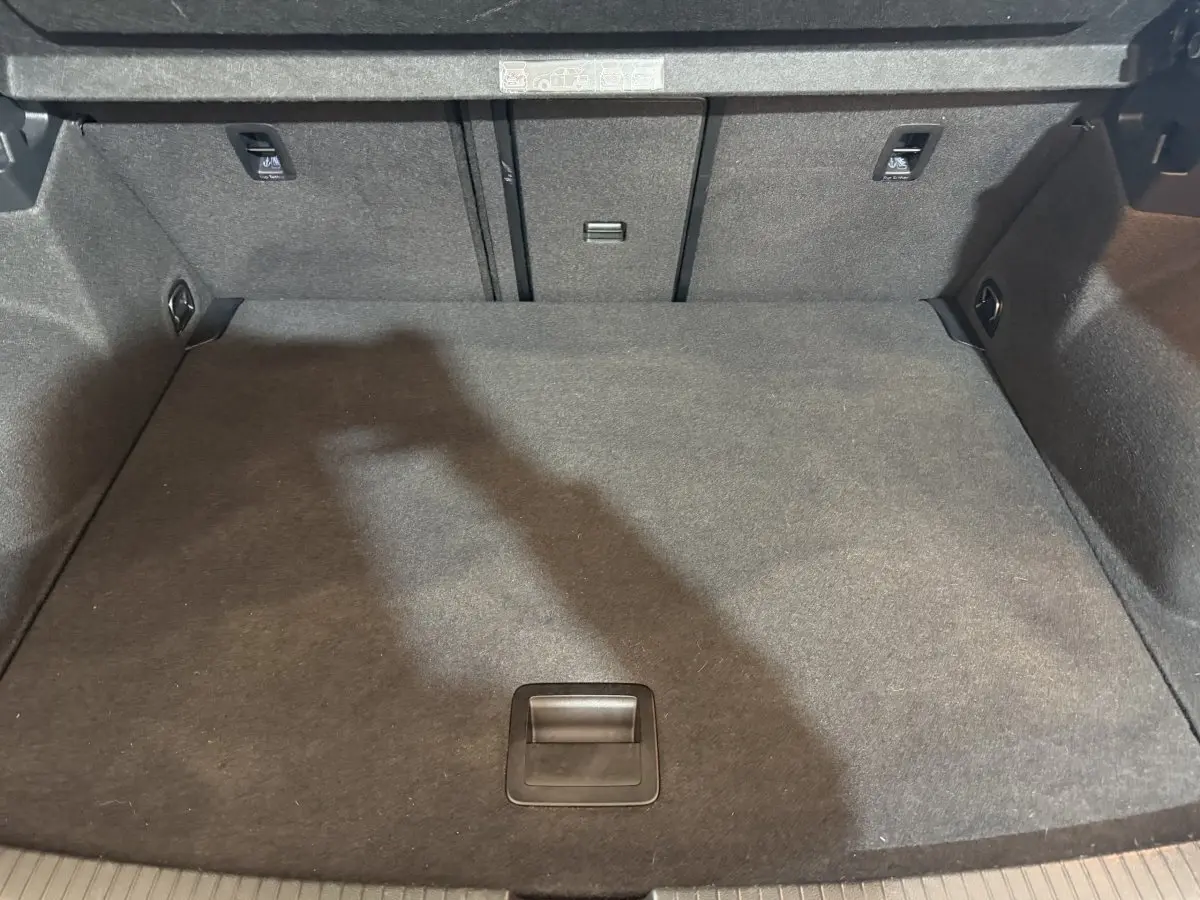 Coffre spacieux et propre du Volkswagen T-Roc noir, vue plongeante montrant le tapis de sol et les fixations arrière.