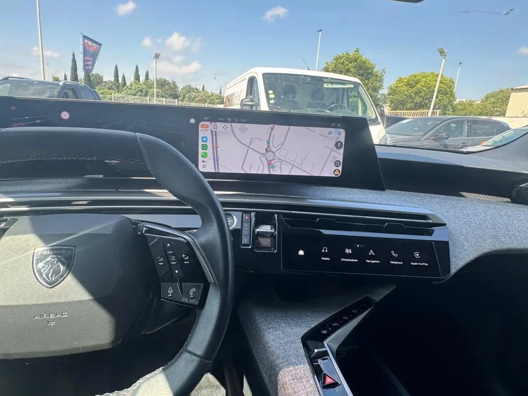 Vue intérieure du tableau de bord du Peugeot 3008 Hybrid 2025, avec volant compact, écran tactile et navigation affichée.