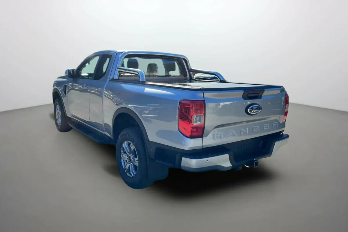 Vue 3/4 arrière droite du Ford Ranger gris iconic avec arceaux inox et bac de benne couvert par rideau coulissant.