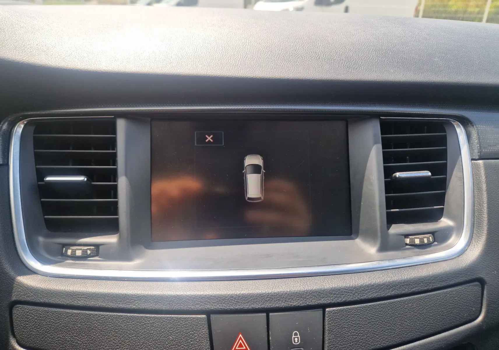 Vue rapprochée de l’écran central du tableau de bord de la Peugeot 508 SW 2015, entouré de grilles d’aération noires.