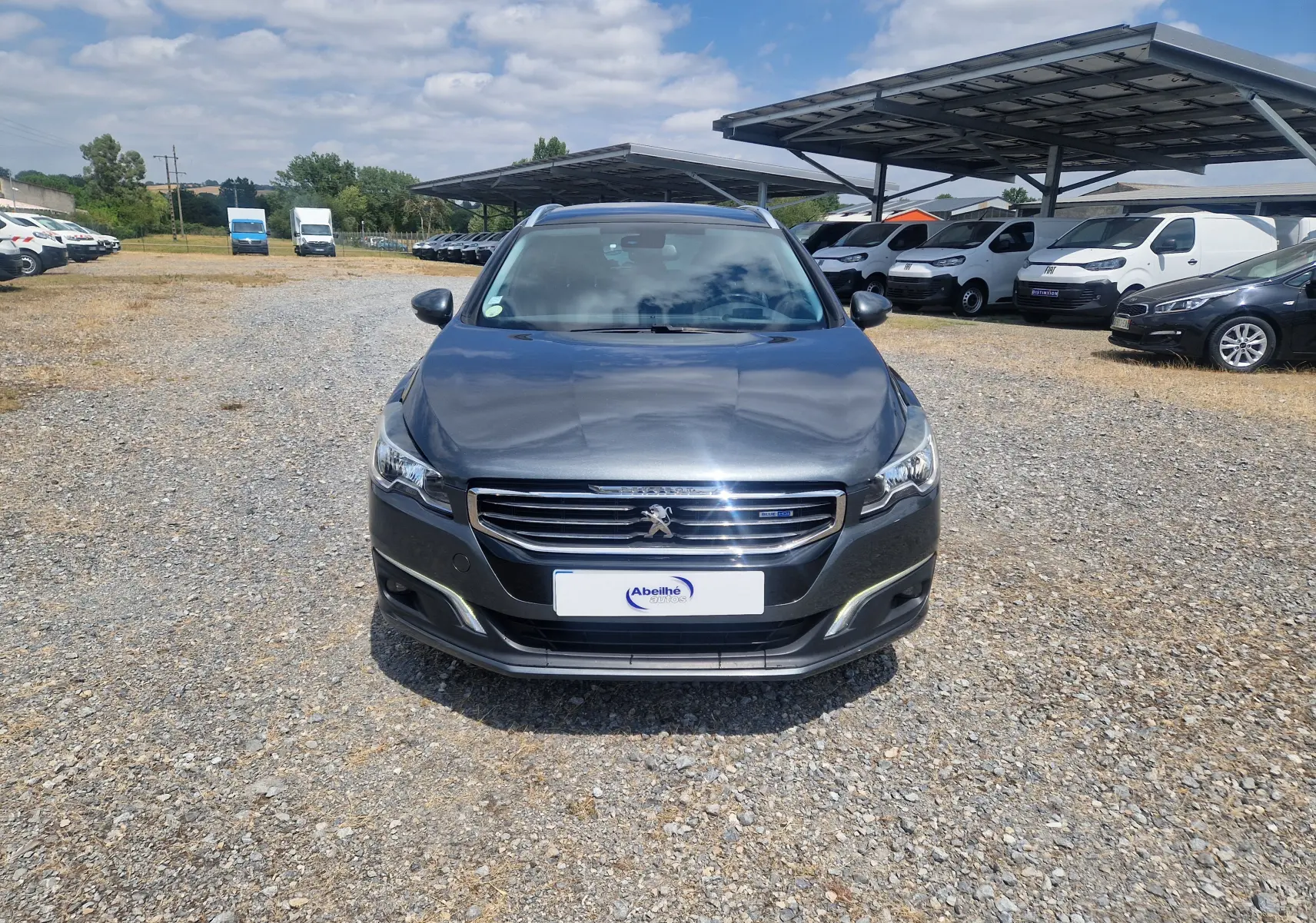Vue frontale d'une Peugeot 508 SW gris shark 2015, avec calandre chromée et phares LED visibles.