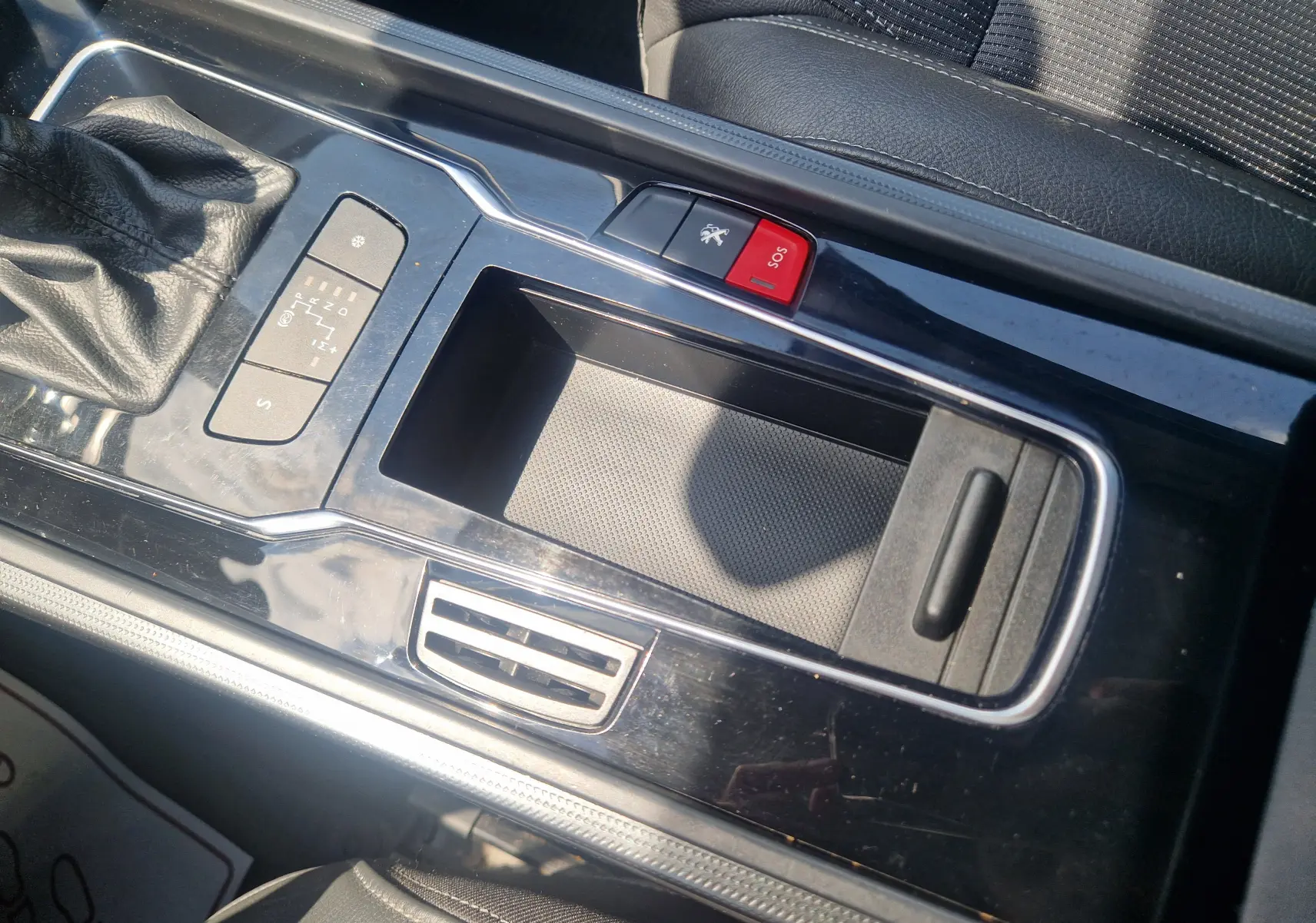 Vue rapprochée de la console centrale noire brillante du Peugeot 508 SW avec bouton SOS rouge et levier de vitesses cuir noir.