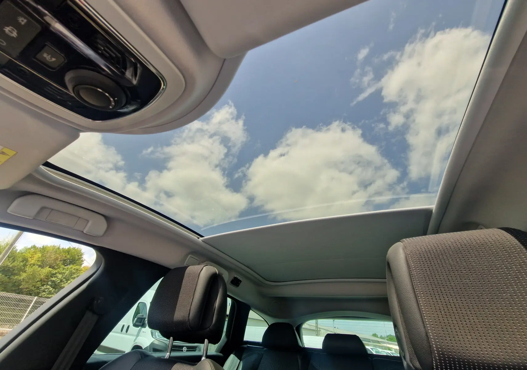 Vue intérieure du toit ouvrant panoramique du Peugeot 508 SW gris Shark, mettant en valeur les sièges avant et arrière en cuir.