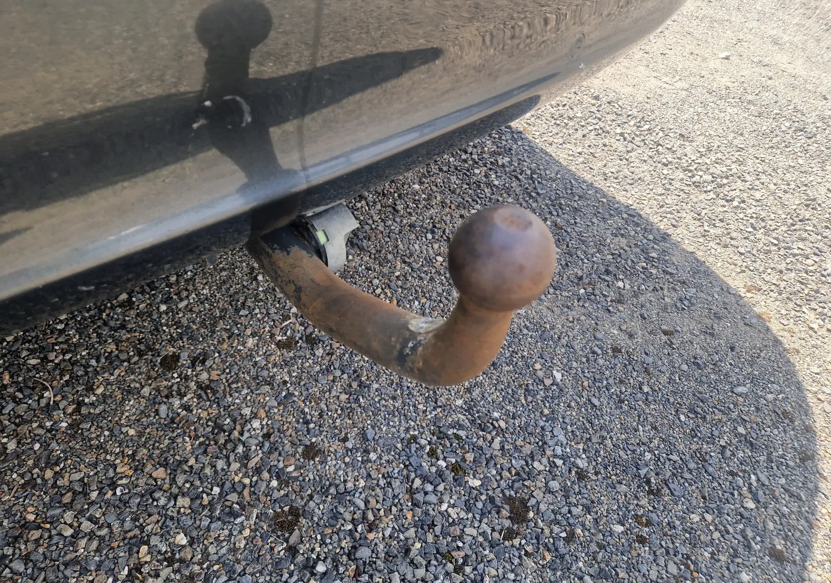 Gros plan sur la boule d'attelage rouillée sous le pare-chocs arrière d'une Peugeot 508 SW gris shark.