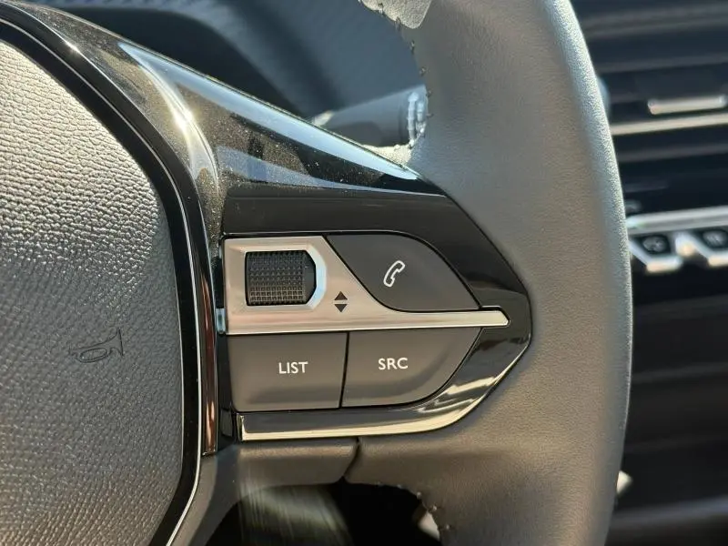 Gros plan sur les commandes gauche du volant de la Peugeot 208 gris Selenium, avec boutons audio et appel.