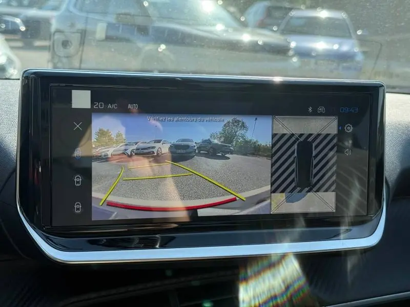 Écran tactile intérieur montrant la caméra de recul et vue 360° du stationnement du Peugeot 208 gris Selenium.