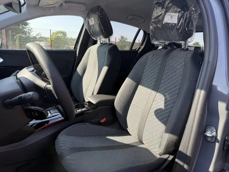 Intérieur de la Peugeot 208 gris Selenium, vue côté conducteur montrant sièges tissu gris et accoudoir central.