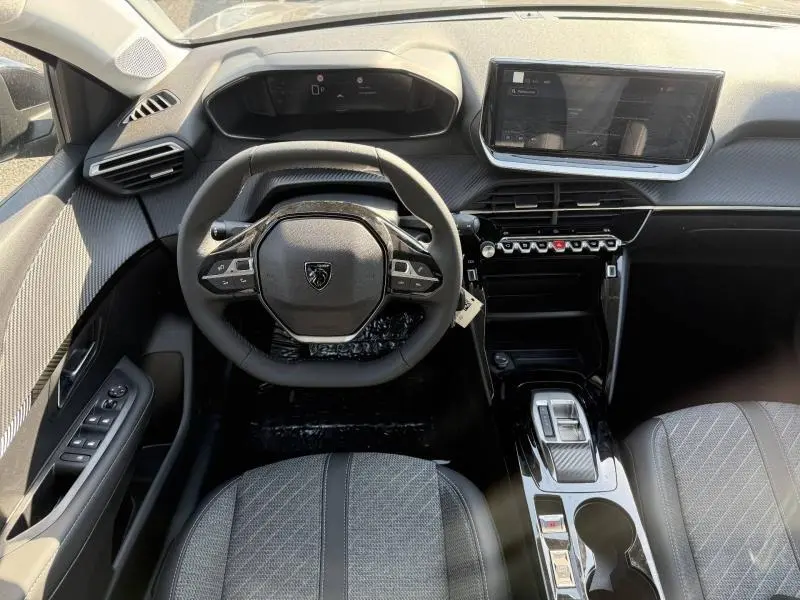 Vue intérieure du poste de conduite de la Peugeot 208 gris Selenium, avec volant compact et écran tactile central.