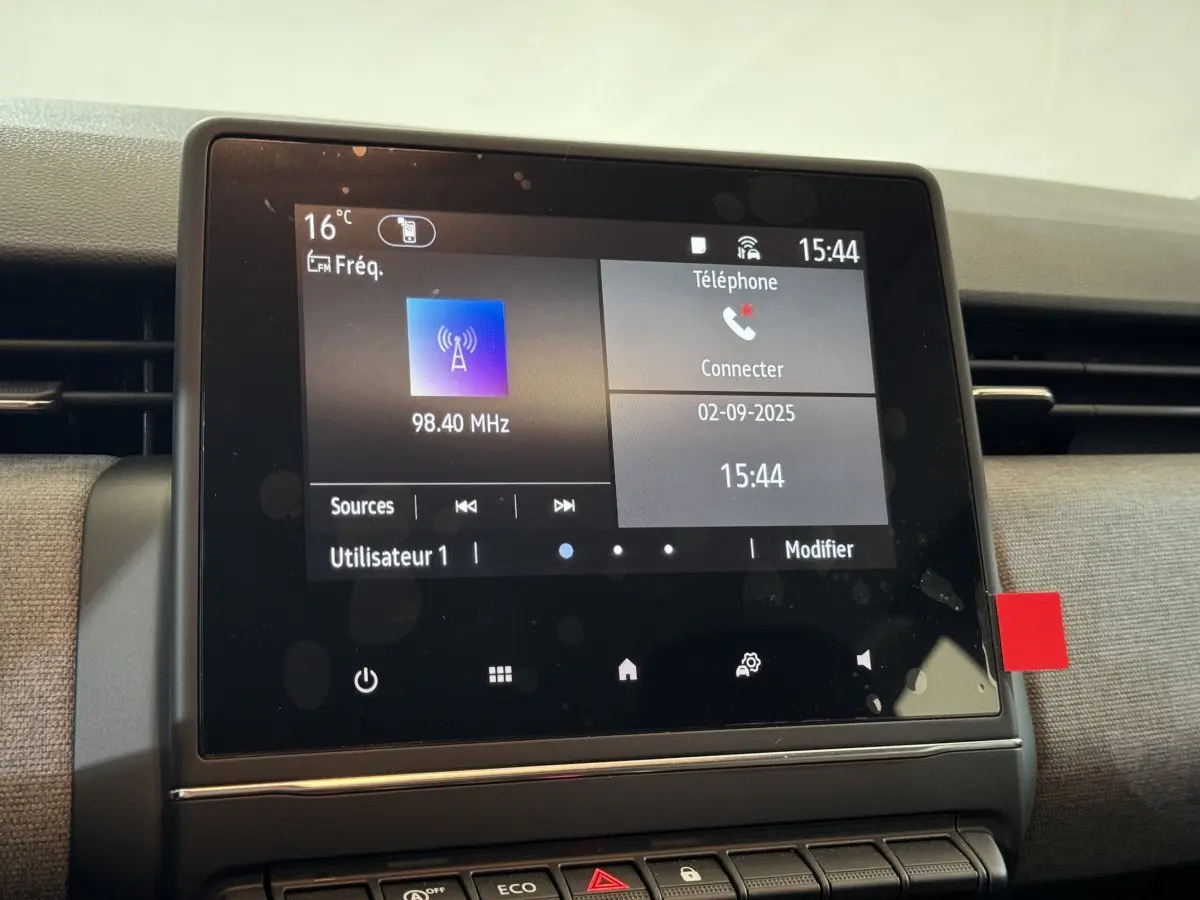 Écran tactile central de la Renault Clio gris clair 2025 affichant radio et connexion téléphone.