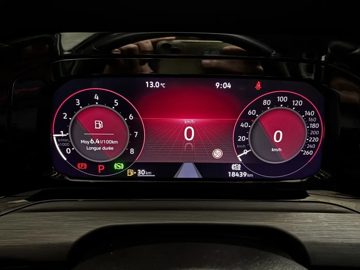 Combiné d'instruments numérique rouge du tableau de bord de la Volkswagen Golf noire 2024, affichant vitesse et consommation.