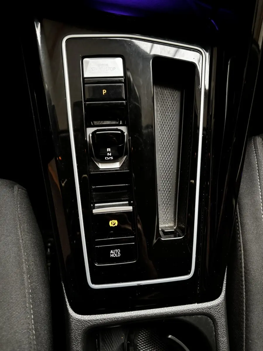 Vue rapprochée de la console centrale noire de la Volkswagen Golf 1.5 ETSI OPF 130 DSG7 Style avec sélecteur de boîte auto et boutons lumineux.