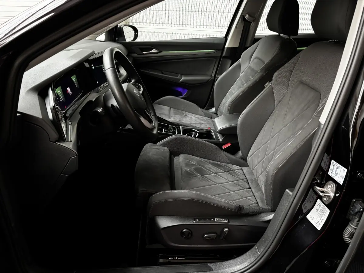 Intérieur avant droit d'une Volkswagen Golf noire 2024, sièges en tissu et alcantara avec tableau de bord digital.