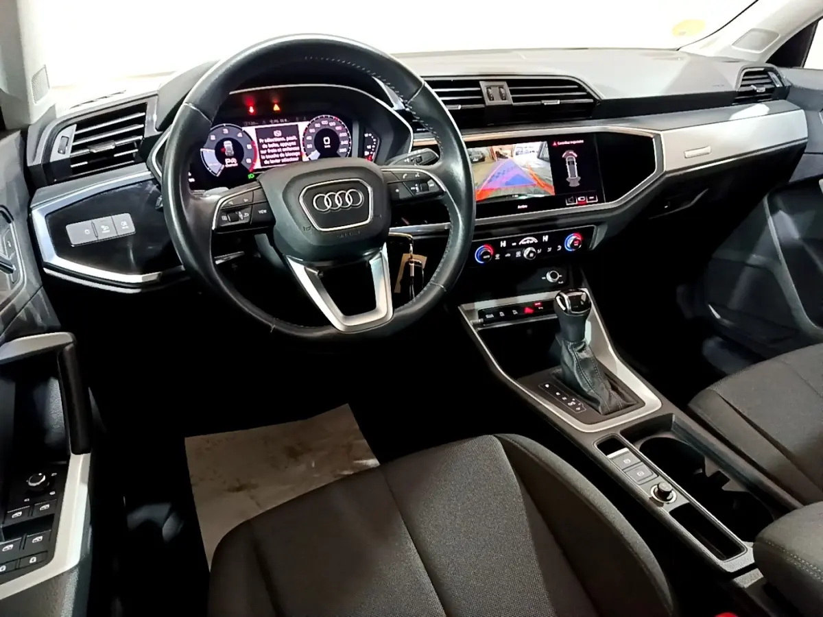 Vue intérieure côté conducteur de l'Audi Q3 35 TDI Business Line 2020 avec tableau de bord numérique et écran tactile central allumé.