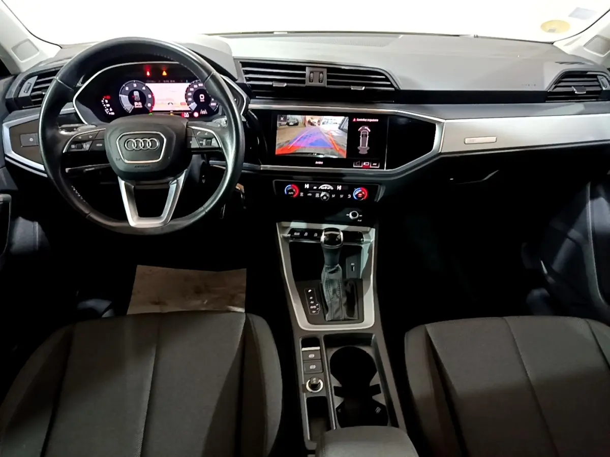 Intérieur noir d'Audi Q3 35 TDI 2020 vu de face, tableau de bord digital et écran tactile central allumé.