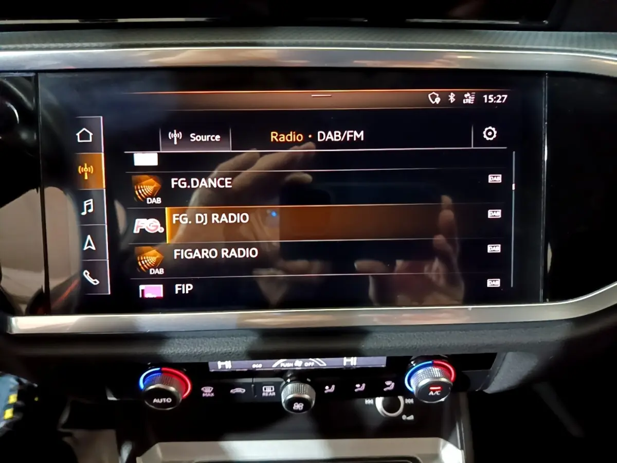 Écran tactile central affichant les radios DAB/FM dans l’Audi Q3 35 TDI Business Line noire, vue intérieure frontale.