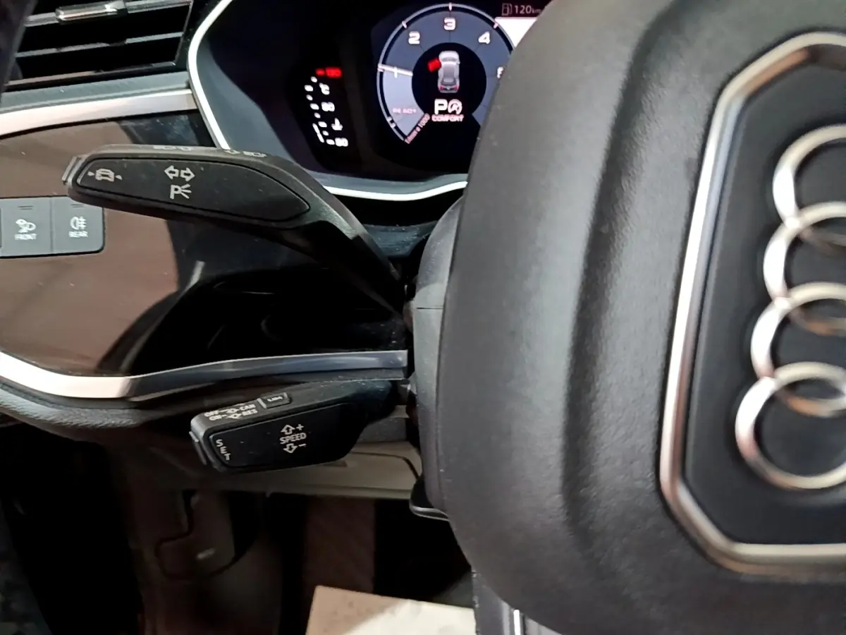 Gros plan sur le volant cuir noir d'Audi Q3 35 TDI 2020 avec commandes au volant et tableau de bord numérique.