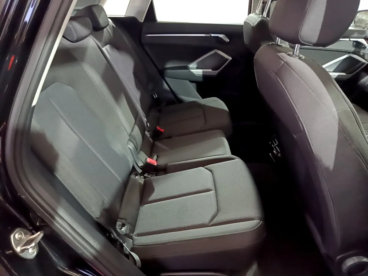 Vue intérieure montrant les sièges arrière noirs du côté gauche de l'Audi Q3 35 TDI 2020 avec garnitures tissu.