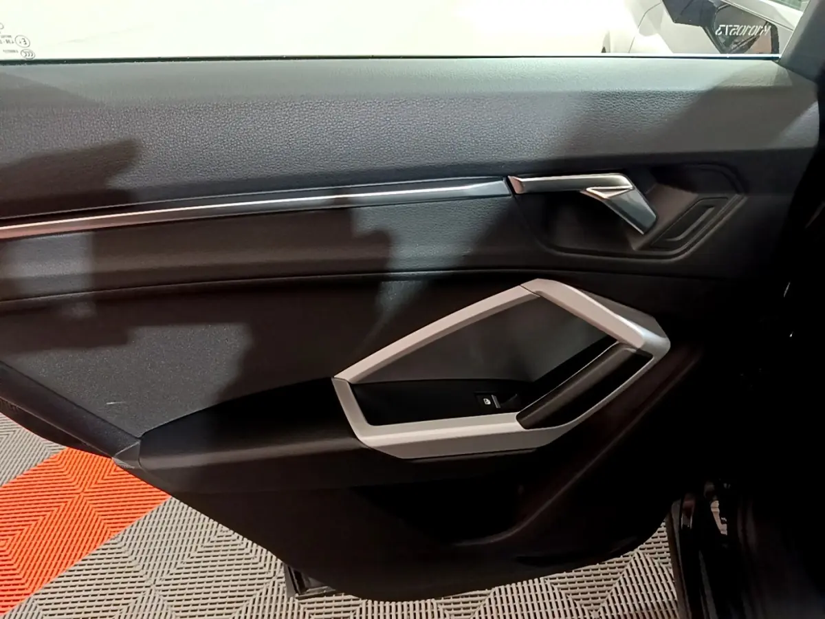 Porte intérieure côté droit noire de l'Audi Q3 35 TDI 150 S tronic Business Line 2020 avec poignée argentée.