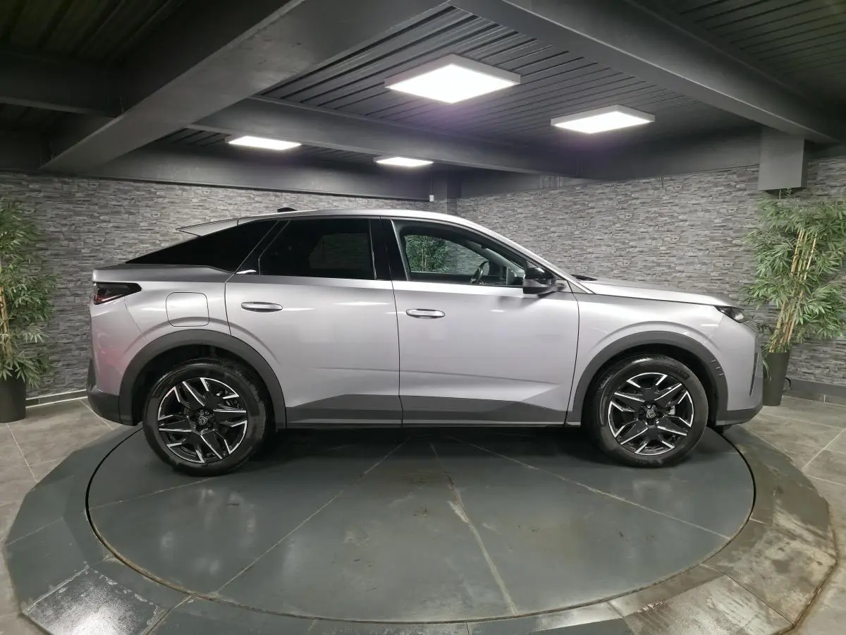 Peugeot 3008 gris métallisé vue de profil côté gauche dans un showroom avec jantes alliage noires.