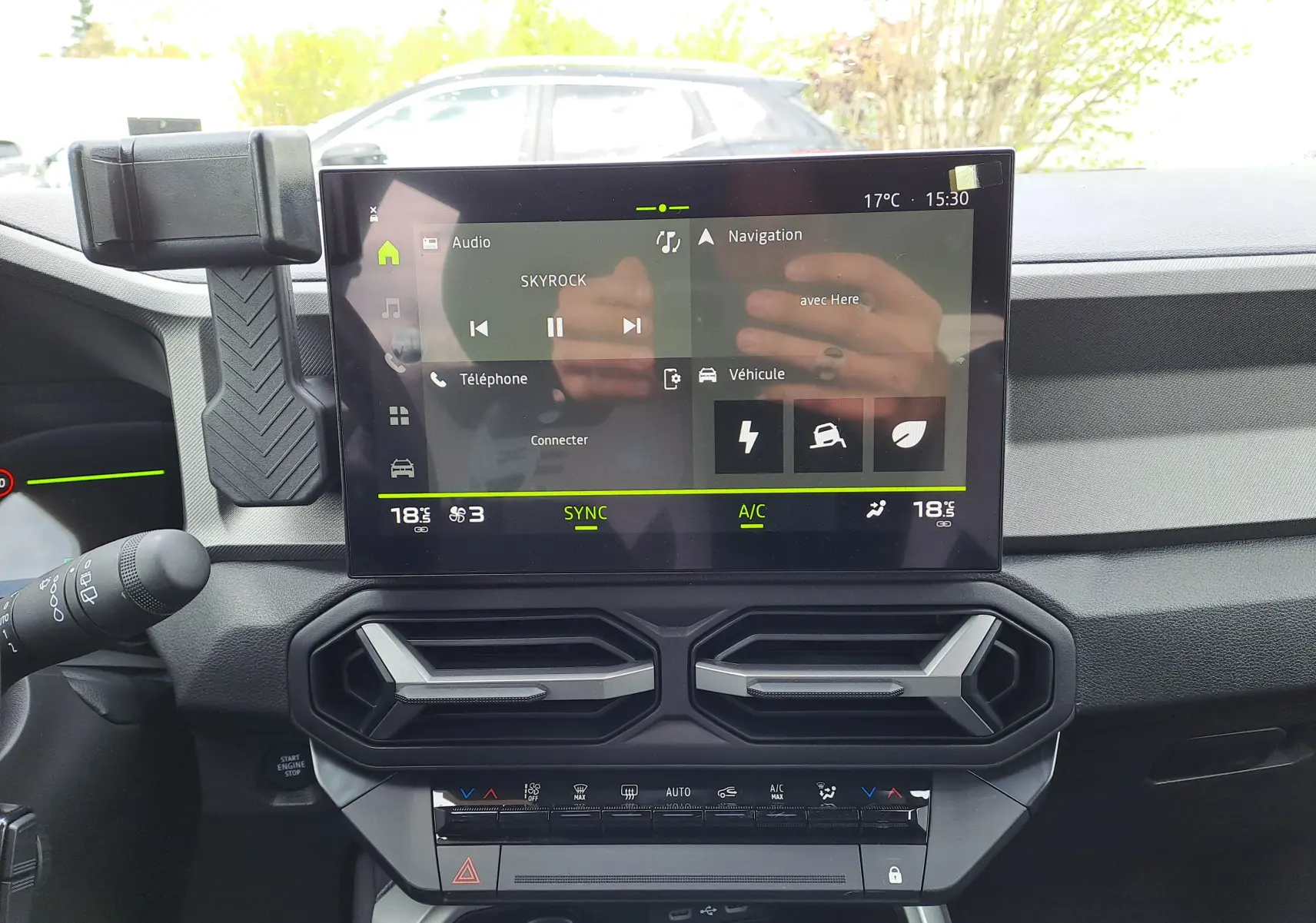 Vue intérieure centrée sur l'écran tactile du tableau de bord du Dacia Bigster, avec commandes de climatisation en dessous.