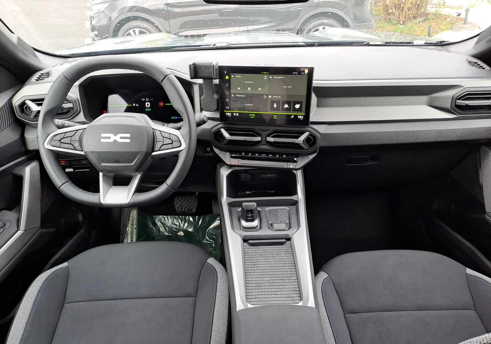 Vue intérieure avant du tableau de bord et volant du Dacia Bigster Hybrid 155 en finition Journey, avec écran tactile central.