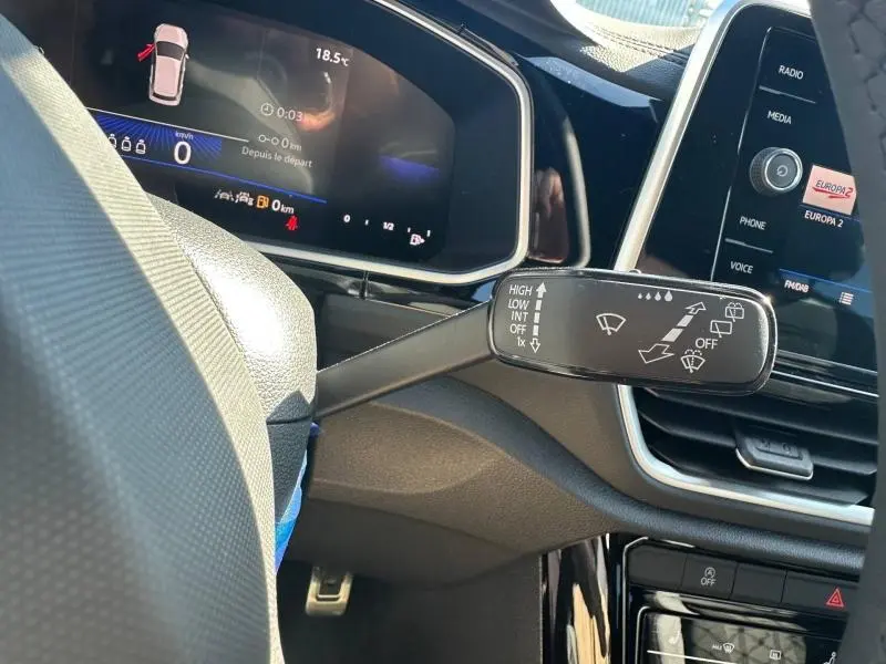 Gros plan sur la commande d’essuie-glace à gauche du volant dans l’habitacle noir du Volkswagen T-Roc 2025.