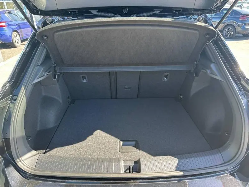 Coffre ouvert vu de l'arrière d'un Volkswagen T-Roc noir intense nacré, espace de chargement propre et vide.