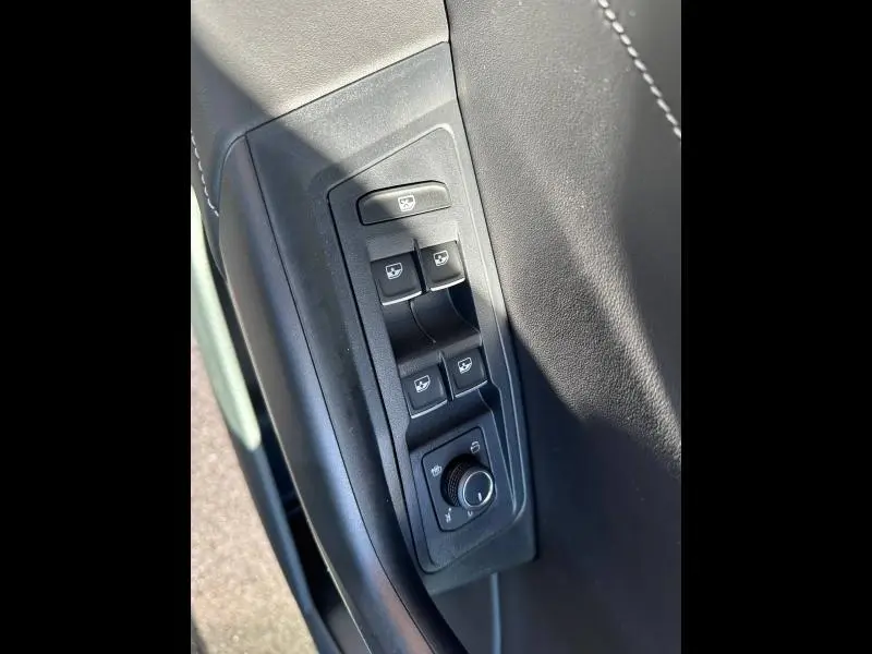 Gros plan sur les commandes de lève-vitres et réglage des rétroviseurs côté conducteur du Volkswagen T-Roc noir nacré 2025.