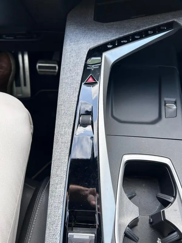 Vue rapprochée de la console centrale grise du Peugeot 3008 Hybrid 136 e-DCS6 GT avec commandes Drive Mode et bouton de warning.
