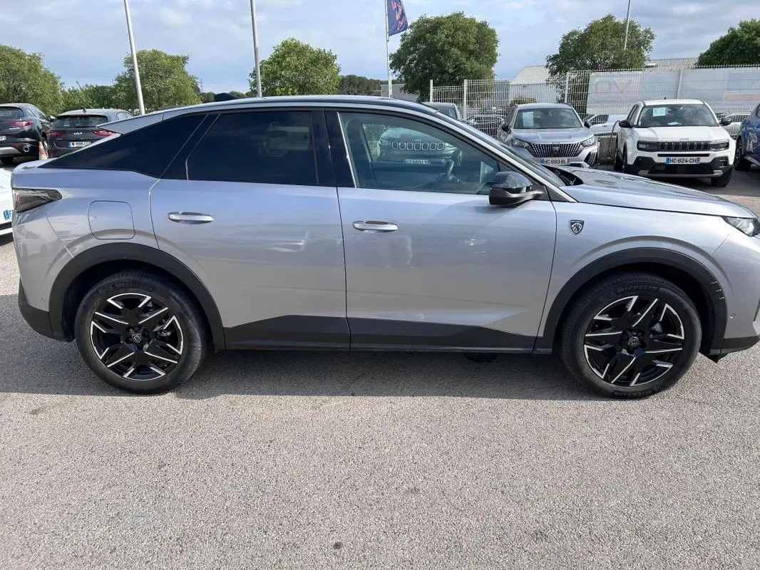 Vue de profil côté gauche d’un Peugeot 3008 Hybrid gris clair avec jantes alliage noires 19 pouces et toit ouvrant.