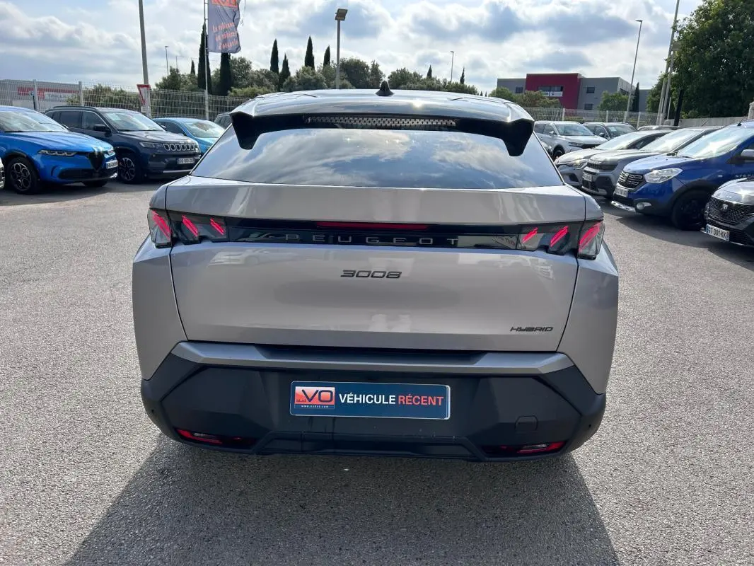 Vue arrière d’un Peugeot 3008 Hybrid gris clair 2025 avec feux LED distinctifs et toit ouvrant visible.