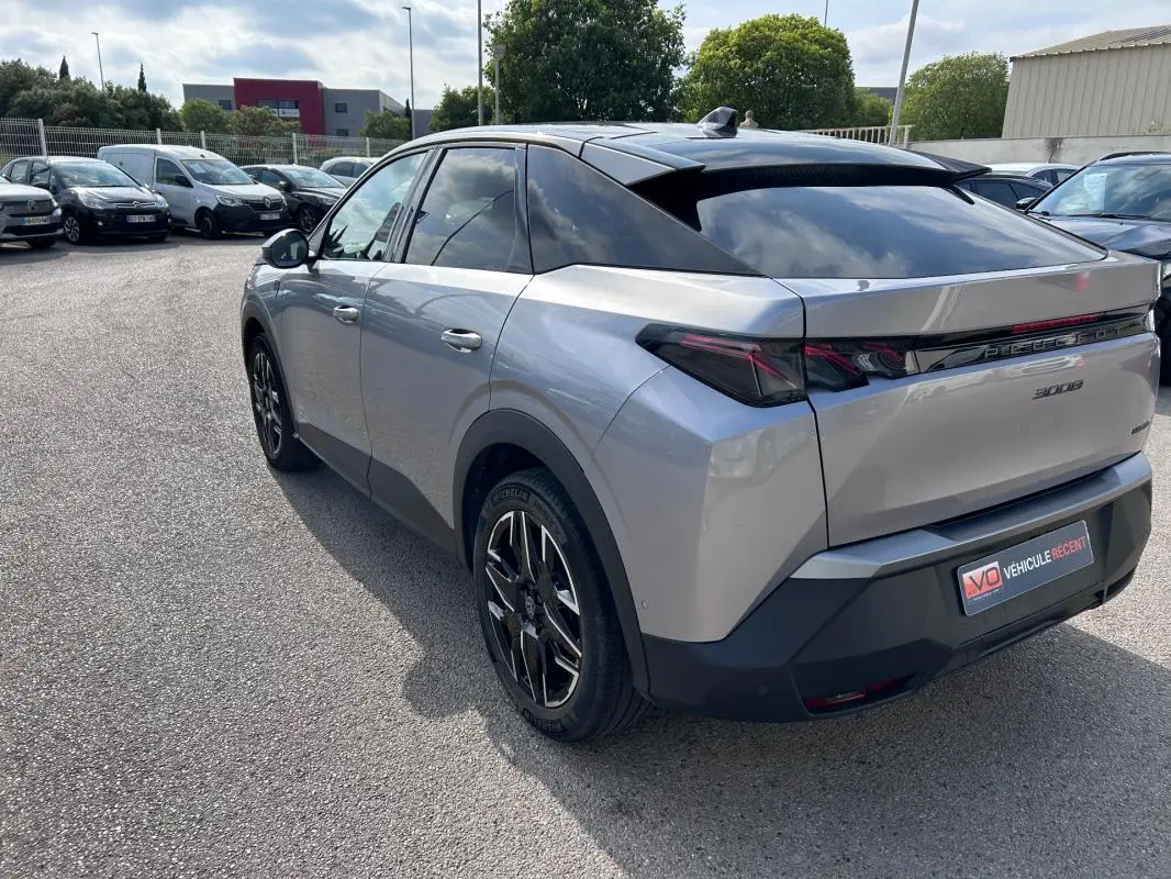 Vue 3/4 arrière droite d’un Peugeot 3008 Hybrid gris clair avec jantes alliage 19 pouces et toit ouvrant noir.