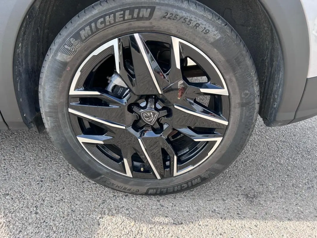 Gros plan sur la jante alliage noire et argent de 19 pouces du Peugeot 3008 Hybrid gris clair, roue avant droite.