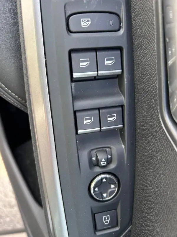 Vue rapprochée des commandes de lève-vitres et réglages des rétroviseurs côté conducteur du Peugeot 3008 Hybrid gris clair 2025.