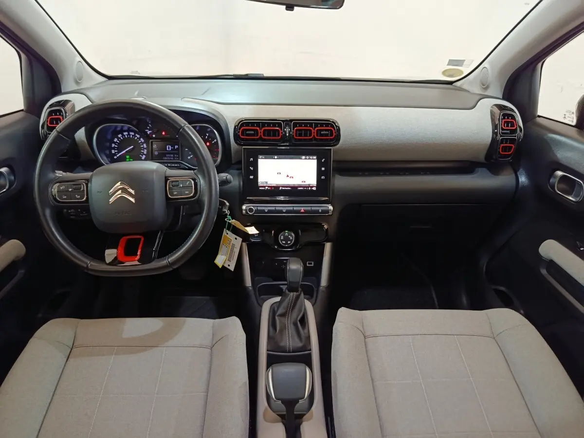 Vue intérieure avant du Citroën C3 Aircross beige 2021, tableau de bord moderne avec écran tactile central et volant cuir.