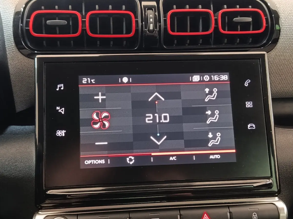 Écran tactile central affichant la climatisation à 21°C, entouré des aérateurs noirs avec contours rouges du Citroën C3 Aircross beige.